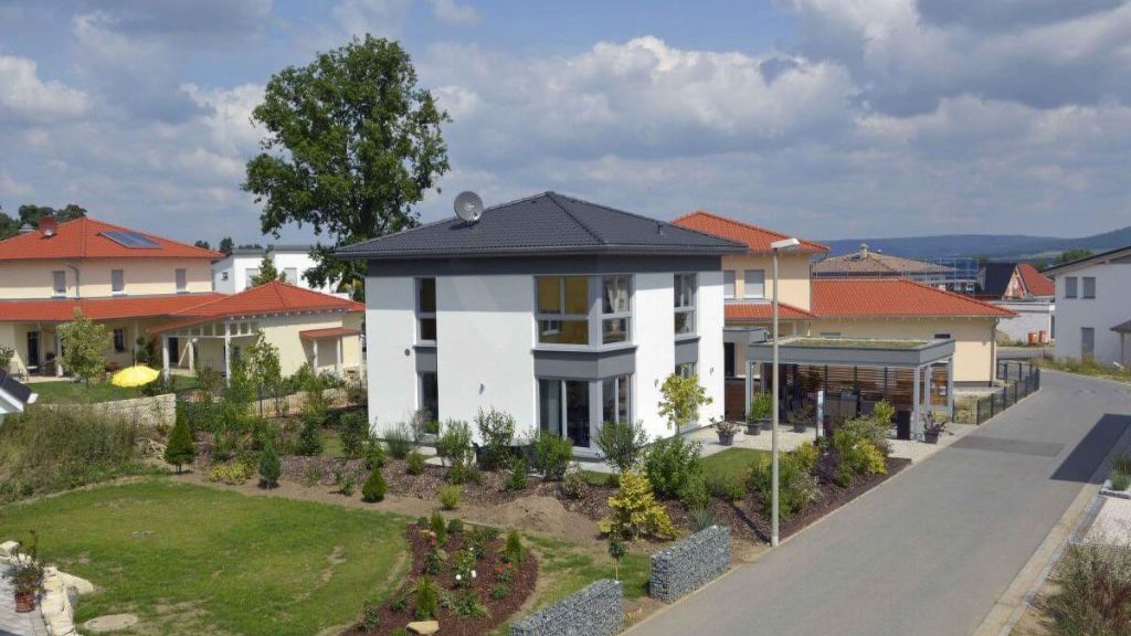 Großes Wohnhaus mit Walmdach und integriertem Carport in Holzständerbauweise.